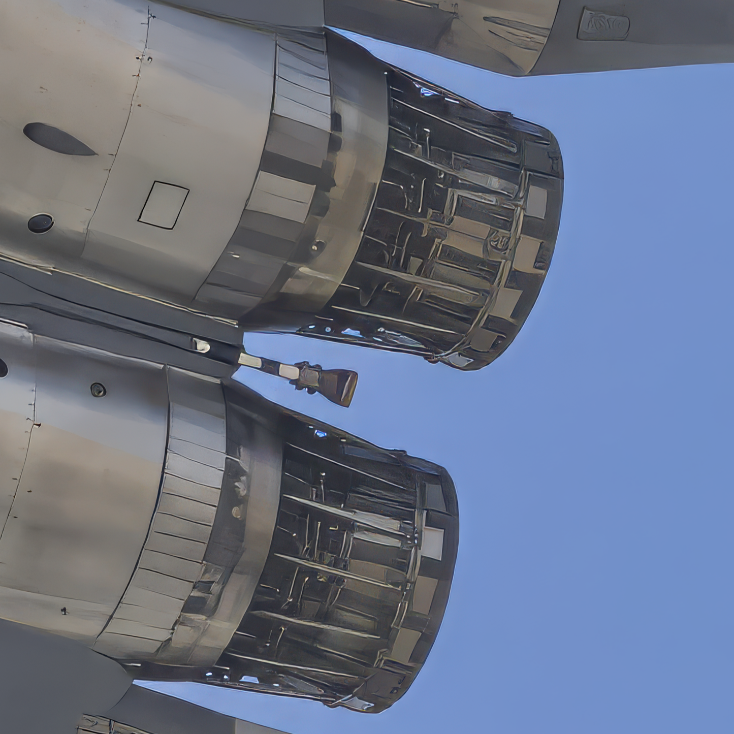 Extreme macro detail view of twin Pratt & Whitney turbofan engine exhaust nozzles on an F-15 Strike Eagle against a blue sky.