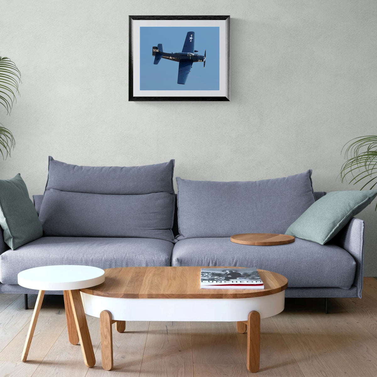 Mighty Spad Douglas A-1 Skyraider framed print centered above a contemporary gray sofa and low wood coffee table.