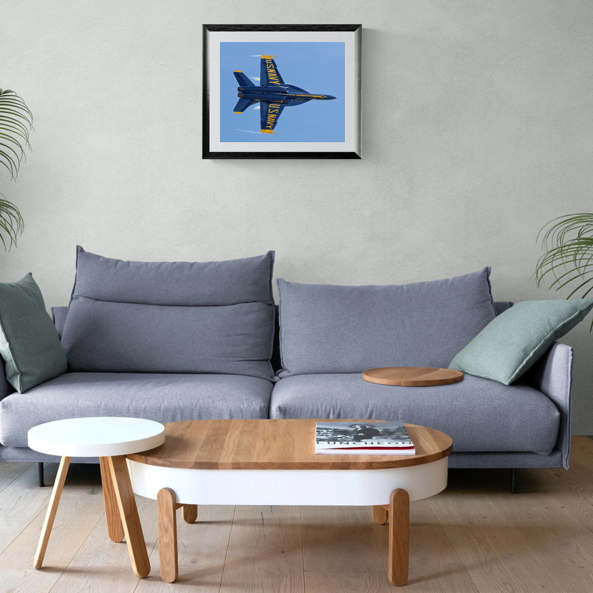 Framed Solo Knife-Edge Pass Blue Angels aviation print hanging on a neutral wall above a modern grey sofa and wood coffee table.