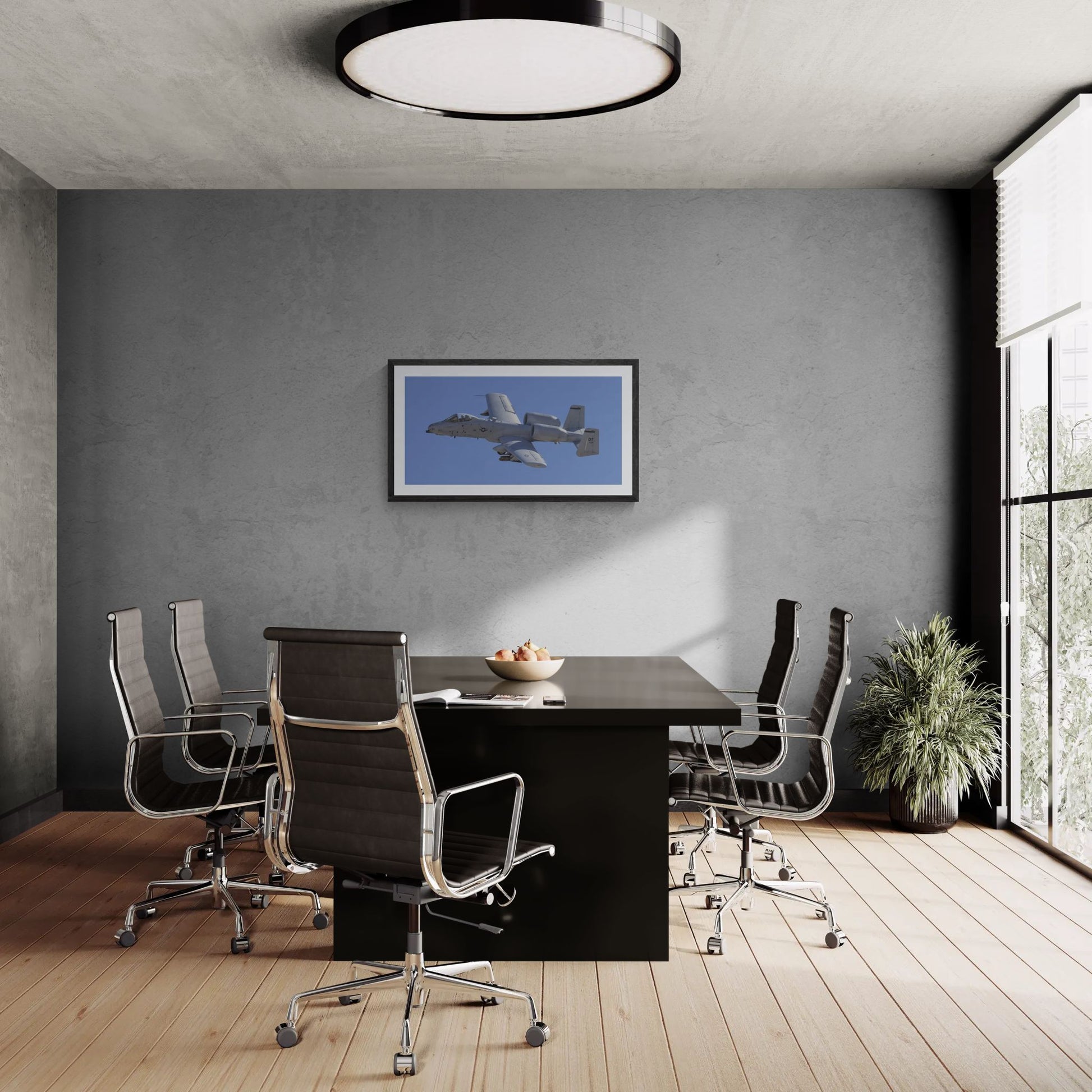 A large-format 40x20 "Statement Edition" of the "A-10 Thunderbolt II: Titanium & Grit" print anchored in a professional boardroom. The panoramic aviation art is displayed on a textured grey feature wall, showcasing the industrial engineering of the A-10 and its commanding presence in a luxury office environment.