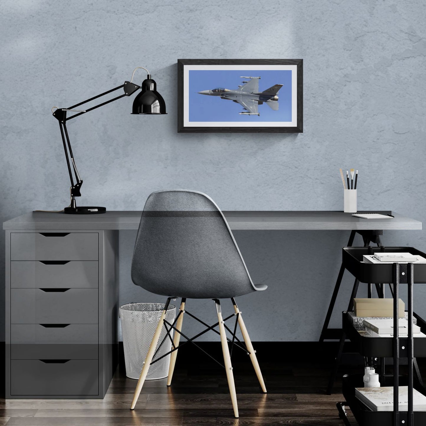 A 20x14 "Standard Edition" of the "Viper Launch" F-16 print featured in a modern home office. The textured black gallery frame anchors the print on a light-blue textured wall above a white desk and a blue ergonomic chair, showcasing its technical detail and scale for a personal workspace.