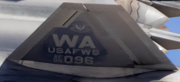 Extreme close-up of the F-22 Raptor tail fin from the "Generations" fine art print. The image reveals the  "WA" tail code and "USAFWS" (US Air Force Weapons School) markings, highlighting the high resolution of the metallic paper.