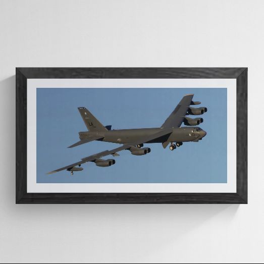 Limited edition B-52 Stratofortress photography print titled "The Industrial Titan" by Phil Schmauder at Nellis AFB. The panoramic master is professionally presented in a textured black gallery frame with a wide white mat against a light gray background, highlighting the rippled fuselage skin and iconic eight-engine profile of the aircraft.