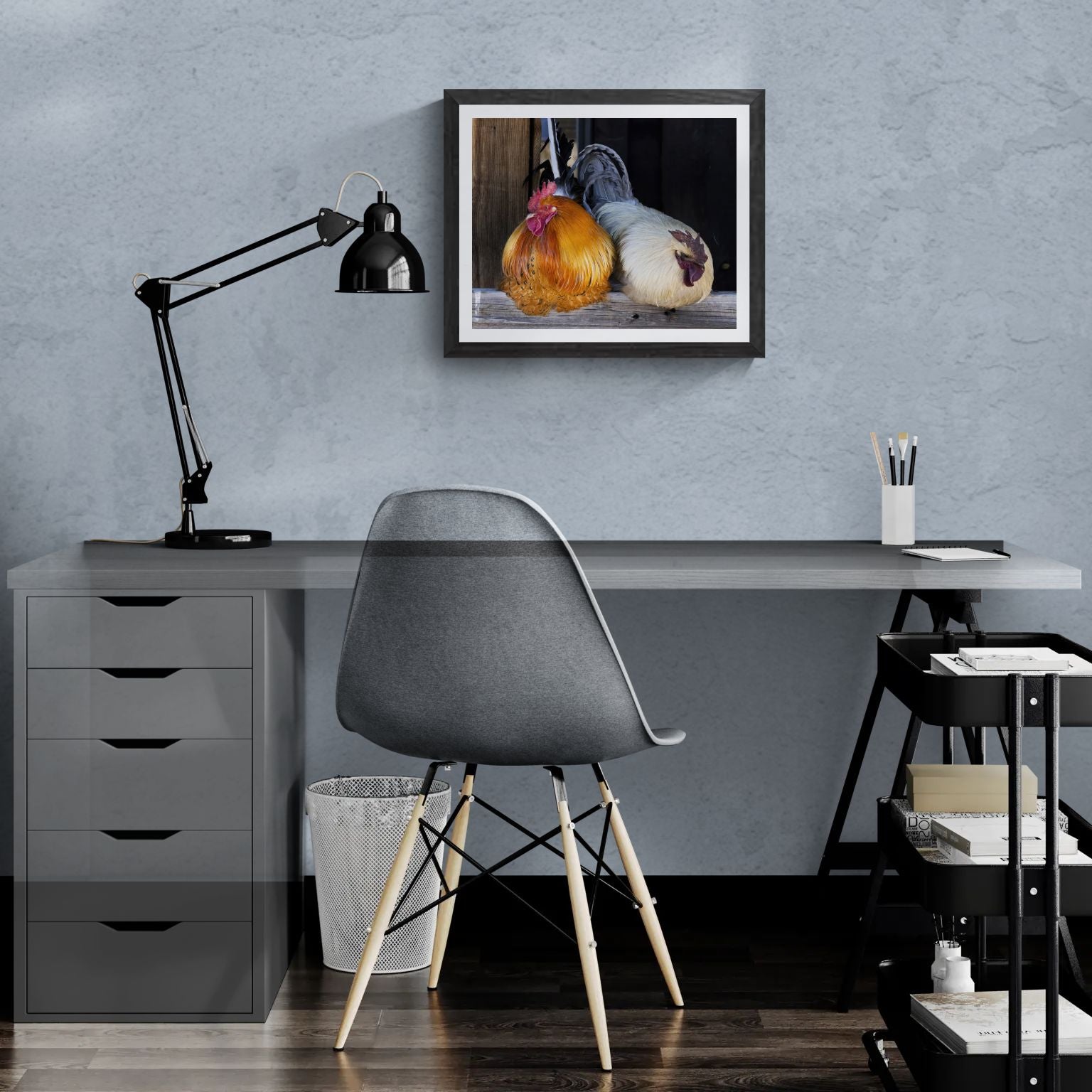 A 20x16 "Standard Edition" of "The Sentinels" barnyard print featured in a modern home office setting. The textured black gallery frame is mounted on a light-blue wall above a white desk, illustrating the print’s scale and vivid biological detail for personal collections.