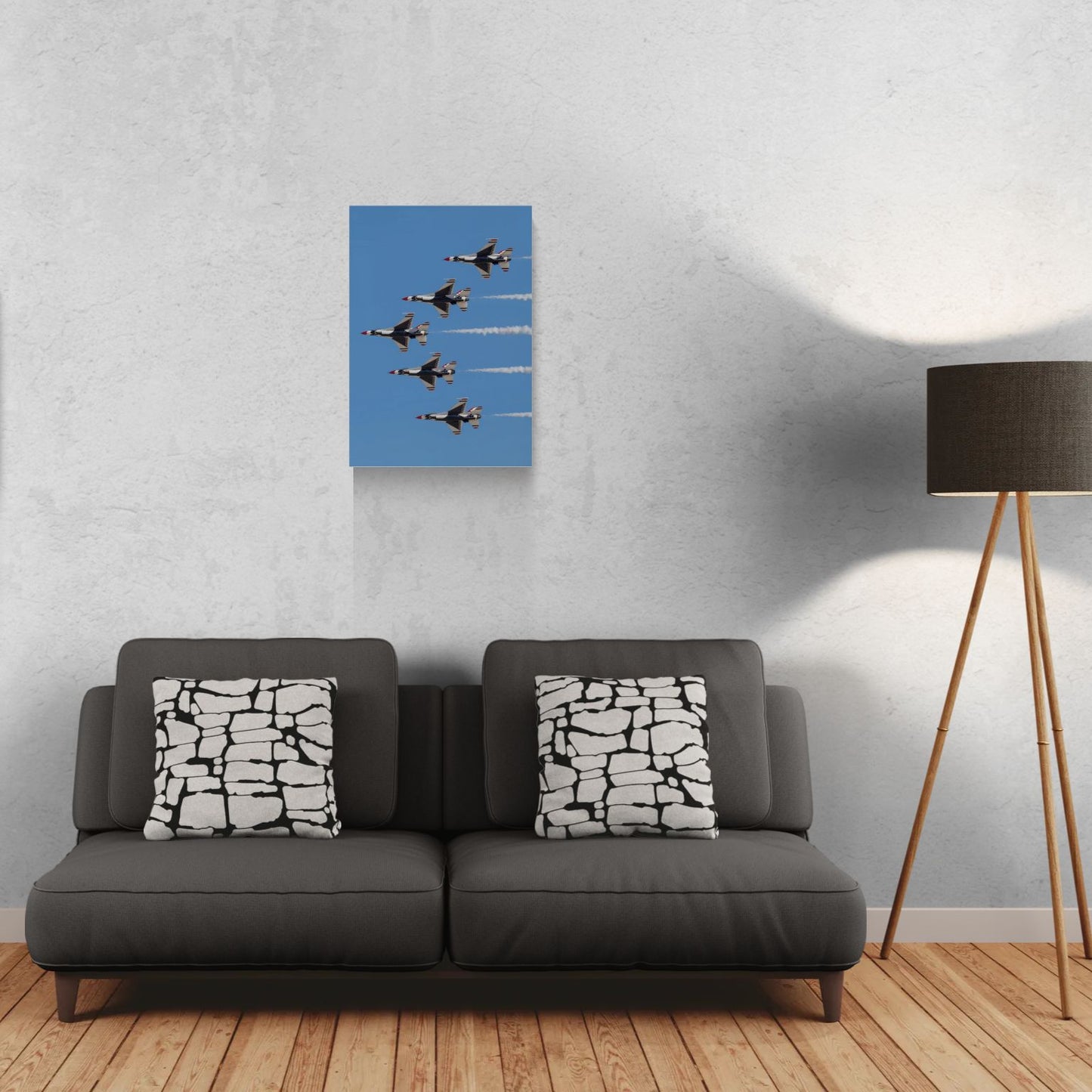 Contemporary residential interior featuring a vertical layout Gallery Edition metal print of a Thunderbirds jet formation, float-mounted frameless on a gallery wall above a luxury dark grey sofa.