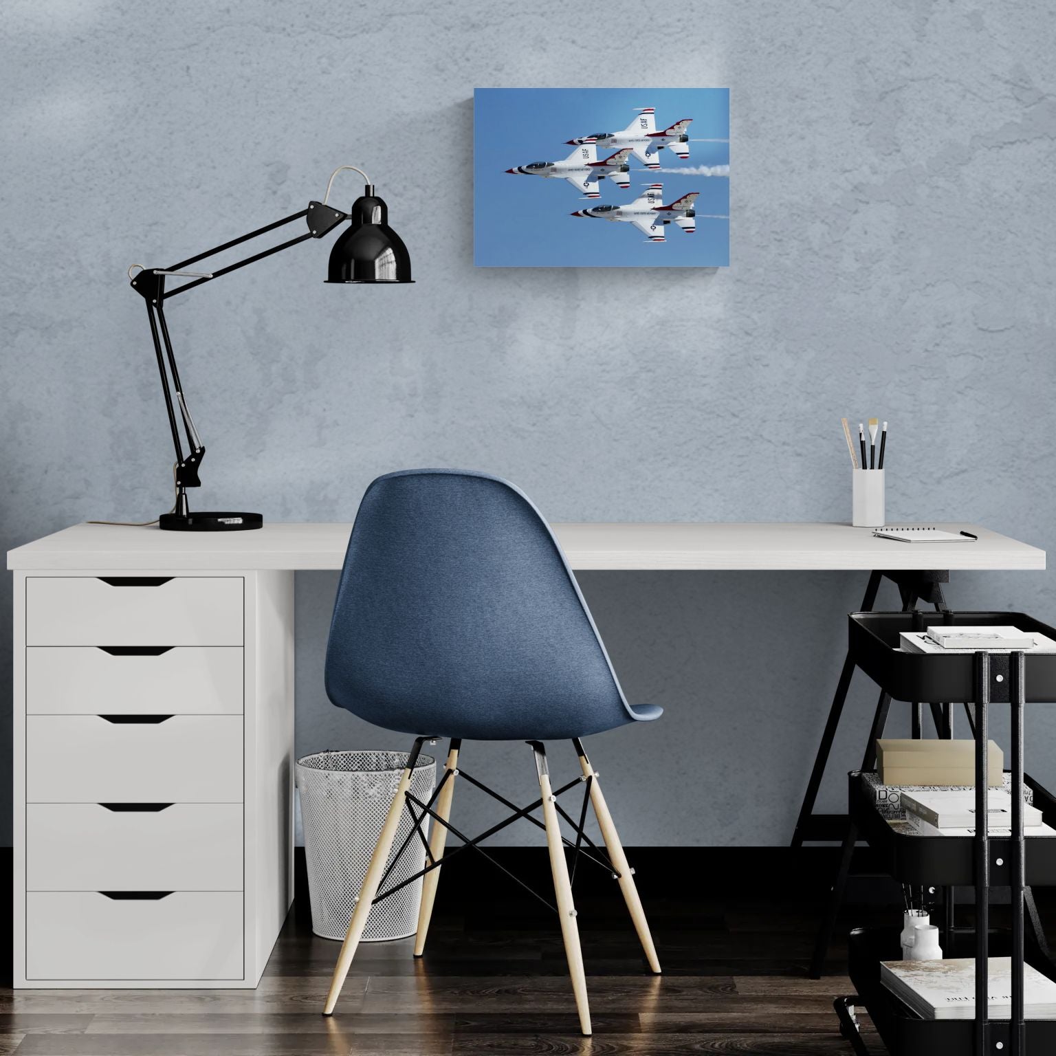 Modern minimalist office workspace featuring a frameless, float-mounted metal aviation print of the Thunderbirds titled Triad Precision by PES Editions, hanging clean on a light-textured wall above a white desk.