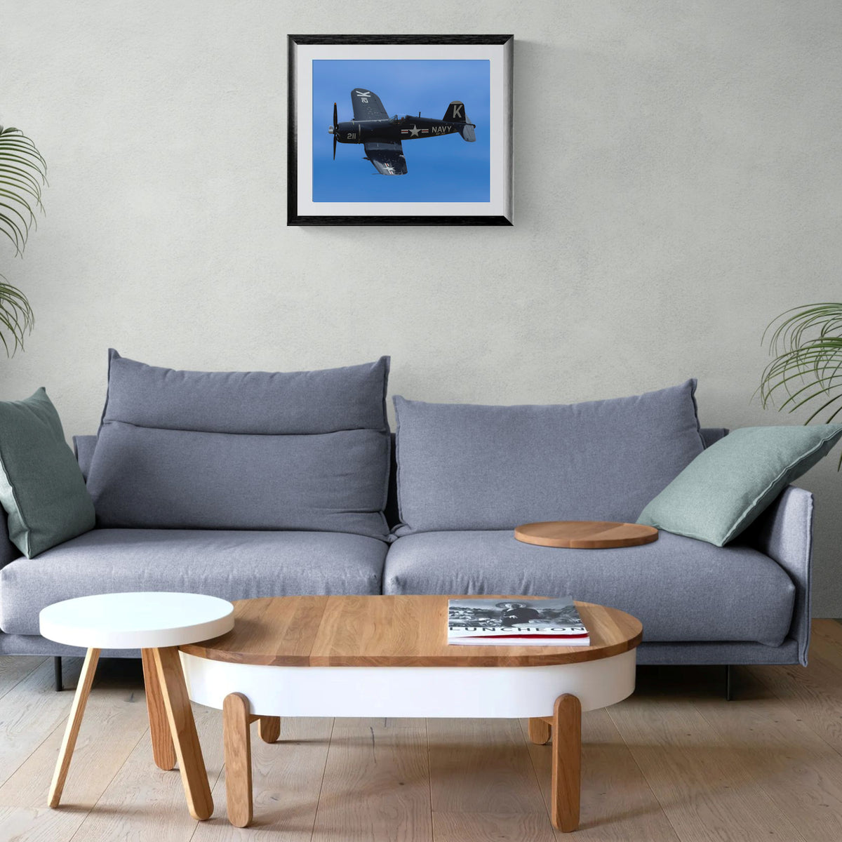 Framed Bent Wing Bird F4U Corsair print centered on a wall above a contemporary gray sofa and modern low coffee table.