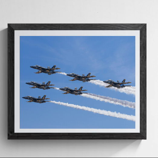 Framed fine art photograph mockup showing a six-ship Blue Angels U.S. Navy flight demonstration delta formation pass against a blue sky, complete with smoke trails, in a dark wood gallery frame.