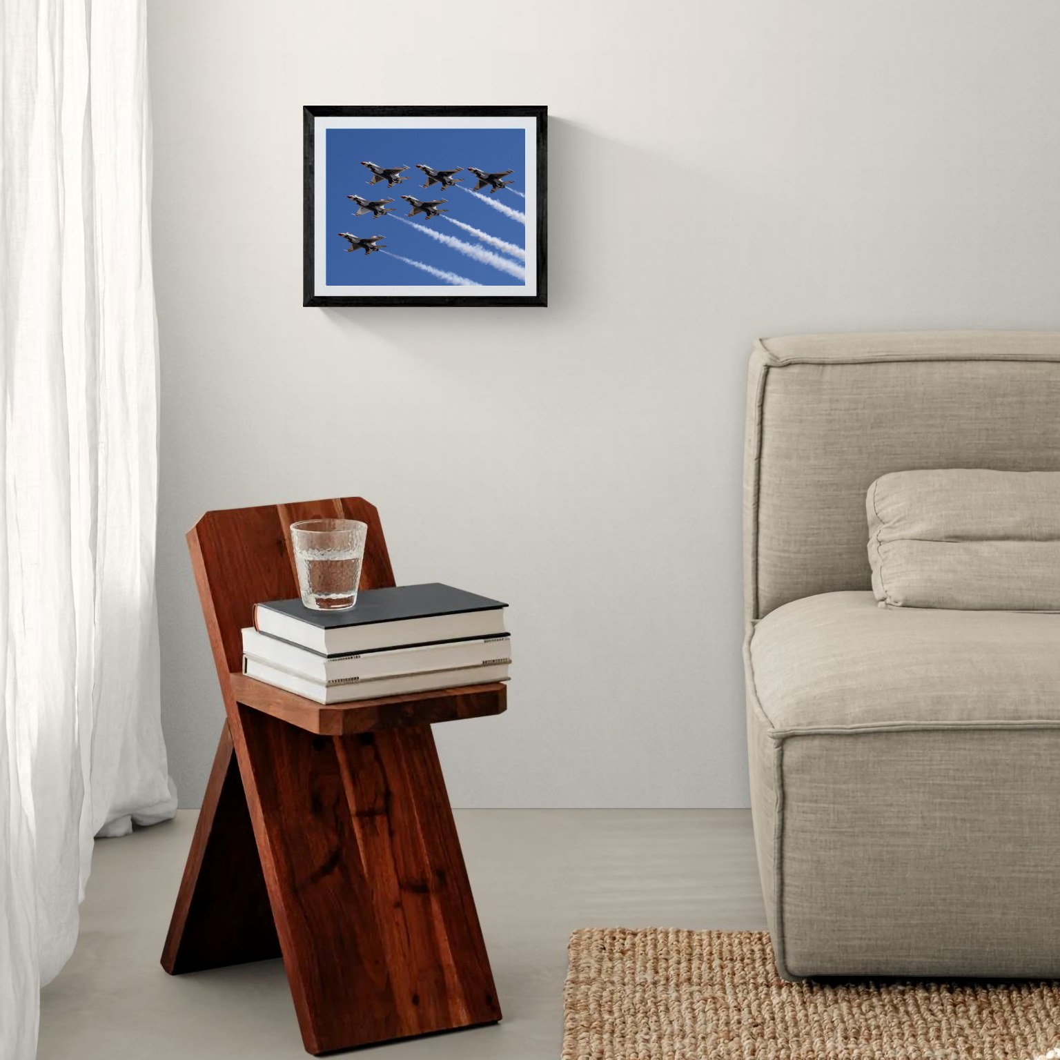 A matted and black-framed fine art print of six Thunderbird jets flying over a deep blue sky, mounted on a neutral wall above a rustic wooden side table in a modern bedroom setting.