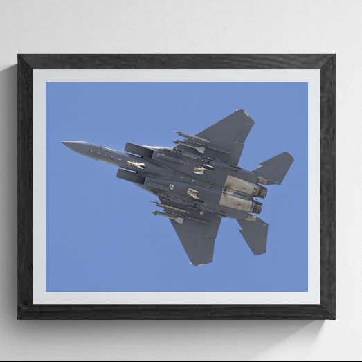 Framed fine art print featuring a bottom-up view of an F-15 Strike Eagle fighter jet banking against a clear blue sky.