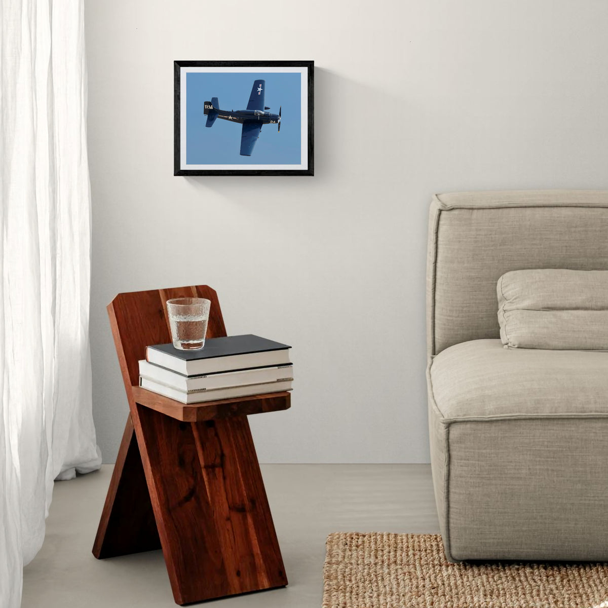 Framed Mighty Spad A-1 Skyraider aviation print mounted on a minimalist wall above a wooden geometric side table beside a neutral sofa.