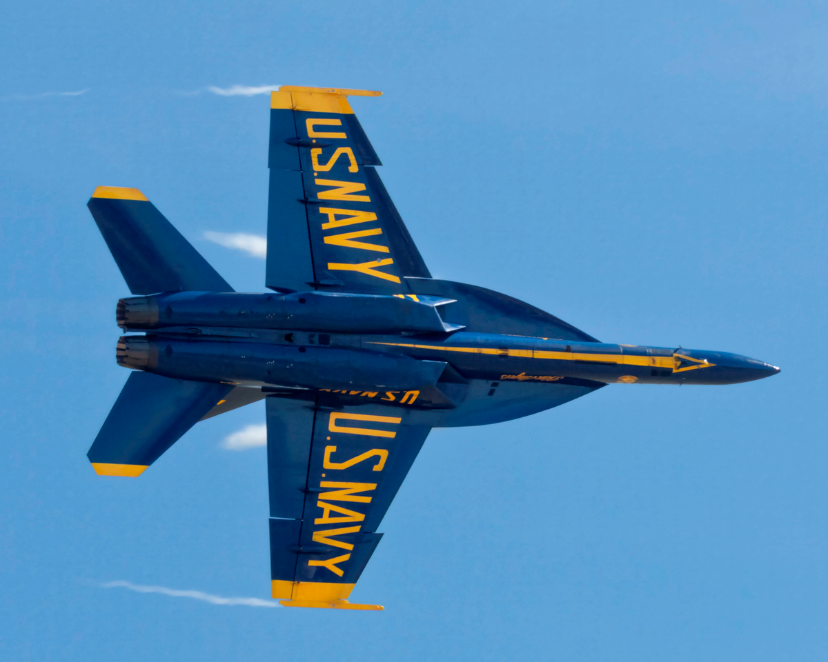 Solo Knife-Edge Pass fine art print by Phil Schmauder showing a Blue Angels F/A-18 Super Hornet banked vertically at ninety degrees against a clear blue sky.