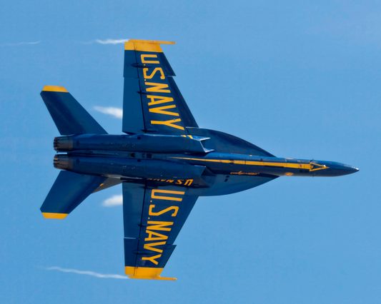 Solo Knife-Edge Pass fine art print by Phil Schmauder showing a Blue Angels F/A-18 Super Hornet banked vertically at ninety degrees against a clear blue sky.