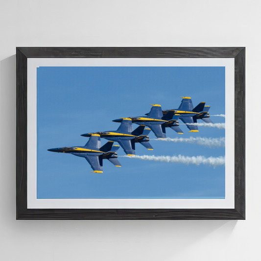 Fine art print of four U.S. Navy Blue Angels F/A-18 Super Hornets flying in tight echelon left formation with smoke trails against a blue sky,