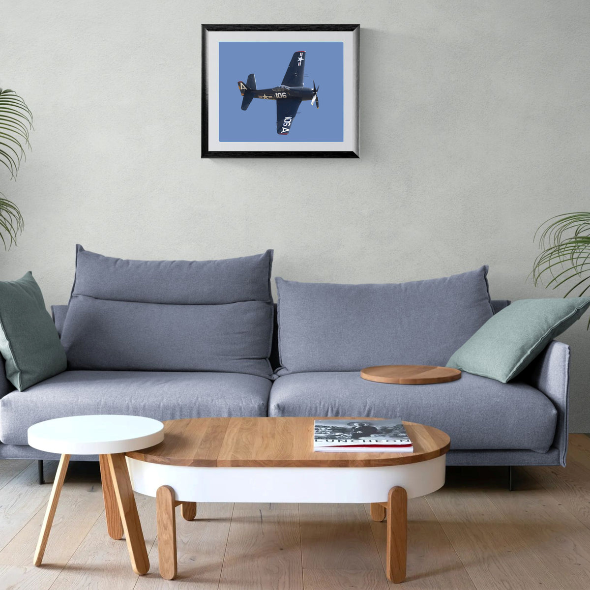 The Final Cat Grumman Bearcat framed print mounted on a wall centered above a modern gray sofa and low wood coffee table.