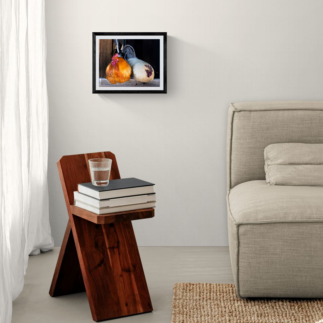 An 11x14 framed fine art print featuring a pair of roosters on weathered wood. The minimalist black gallery frame hangs elegantly on a clean white accent wall above a dark wood side table next to a neutral-toned couch.